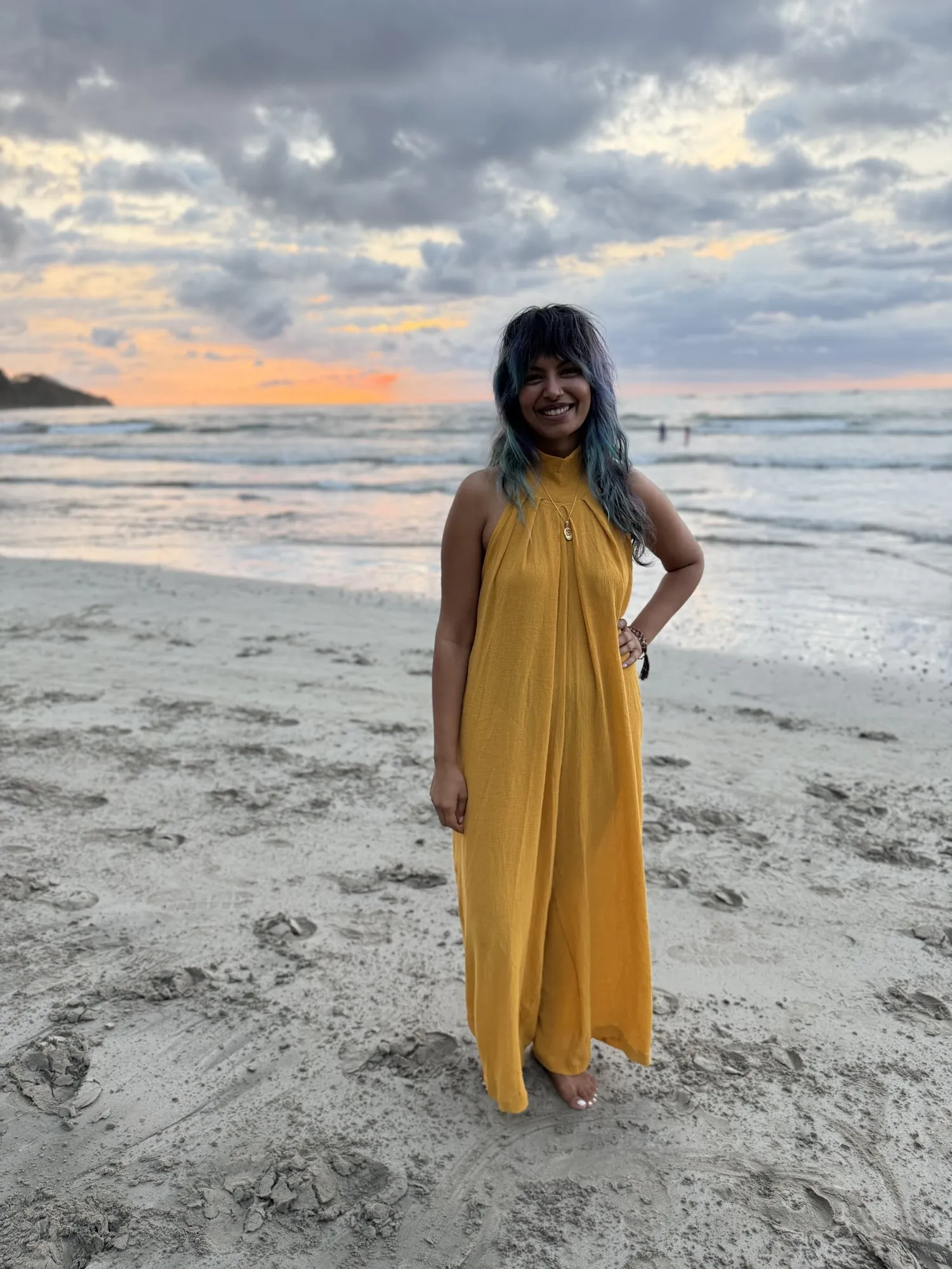 Zineea on a beach at sunset in a yellow dress