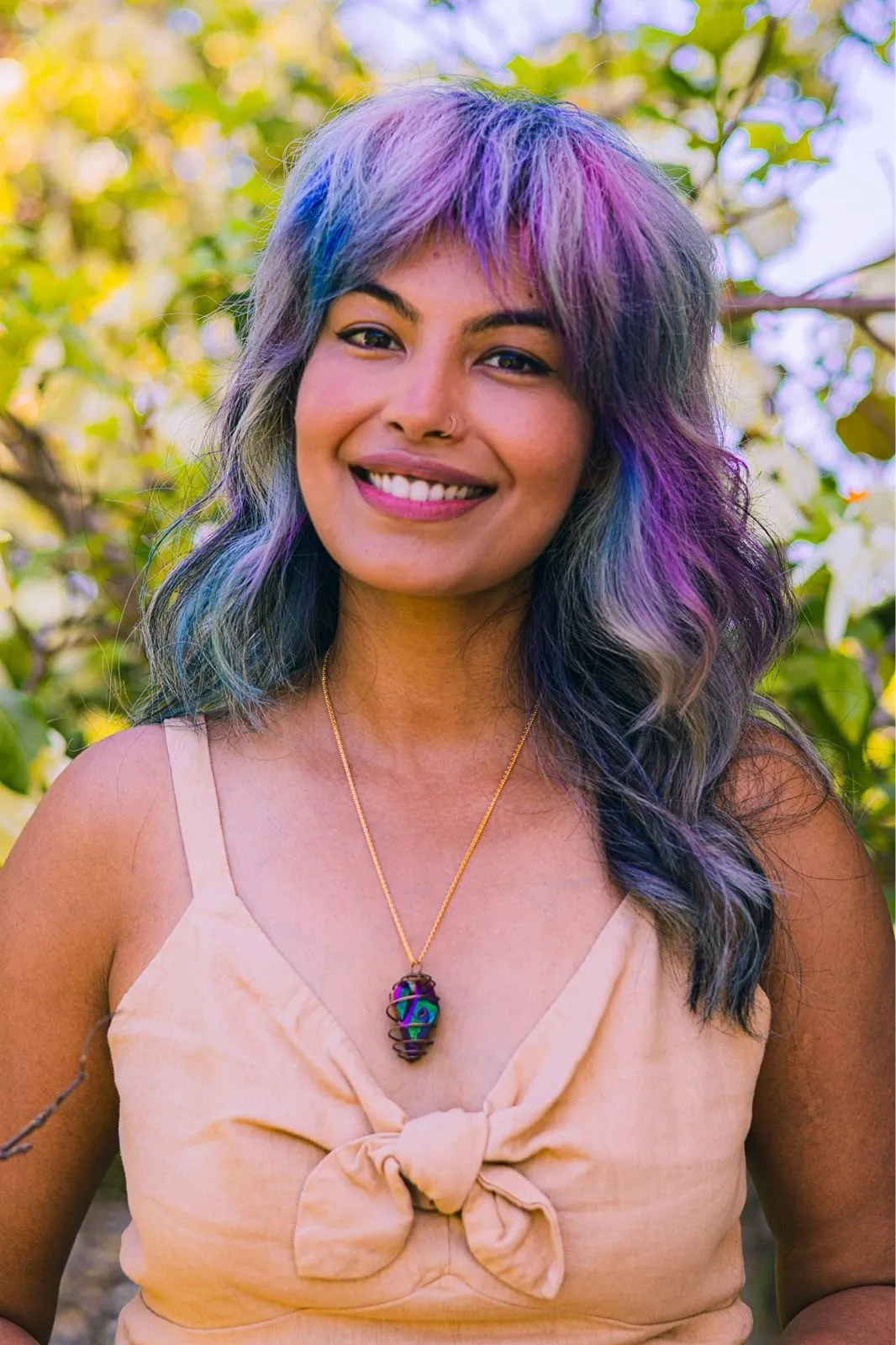Portrait of Zineea in a garden, smiling, wearing a stone pendant