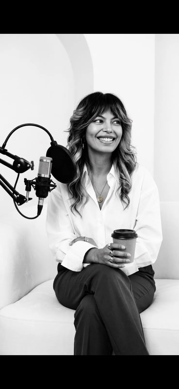 Zineea at the microphone, smiling, coffee in hand