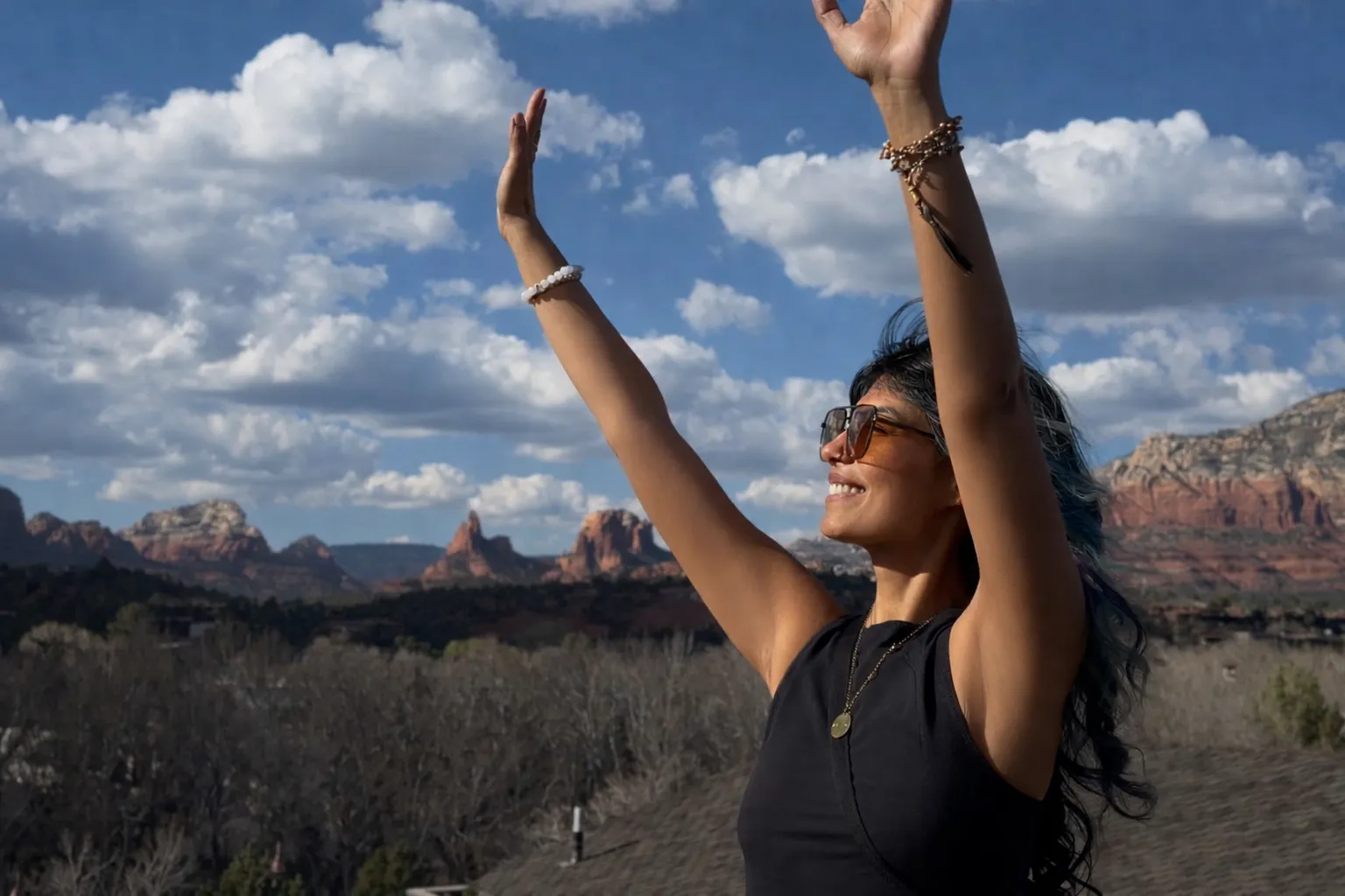 Zineea, arms raised, standing before the red rocks of Sedona, Arizona